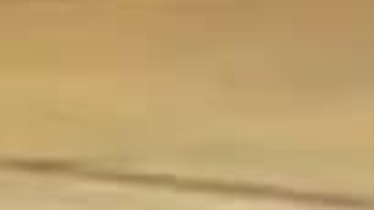 A blurred, featureless pale tan surface
        filling the whole frame. No people, no court, no detail: what a phone sees face down
        on a bench or hard against a wall.